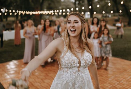 Bride tossing her wedding bouquet to the unmarried wedding guests