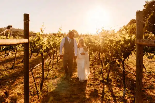 A bride and groom stroll through the Rough & Ready Vineyards