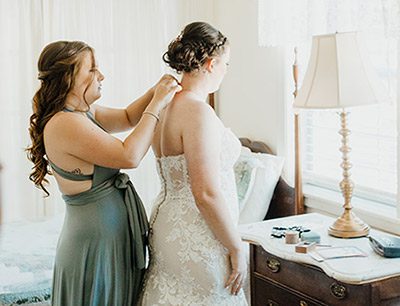 Bridesmaid helping the bride get ready. Photo by Wild Love and Wanderlust