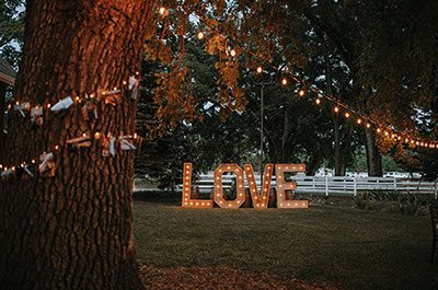 Market lights, twinkle lights, and lighted LOVE letters at an evening wedding. Photo by Photo by Ashton Imagery