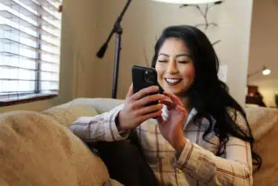 Young woman having fun on a wedding planning app in her living room