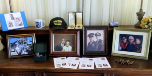 A hutch displaying framed photos and items from the deceased at a memorial