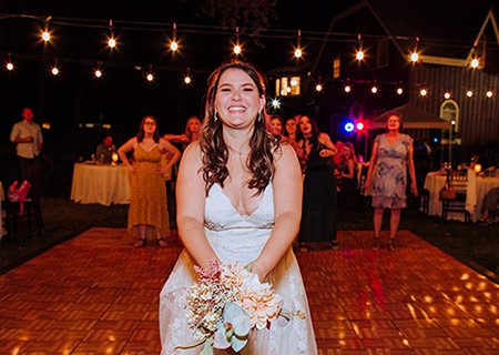 A happy bride tosses her bouquet to single friends. Photo by Athena Kalindi Photography