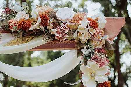 Close-up photo of a floral arrangement on a wedding arch by Athena Kalindi Photography