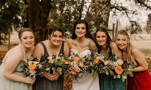 A bride and her bridesmaids smiling despite the rain. Photo by Lela Spiva Photography
