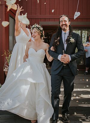 A newly-wedding couple has rose petals thrown during their recessional