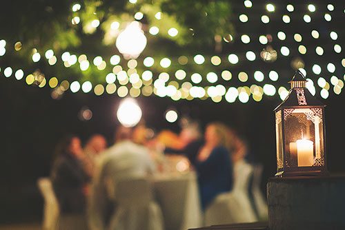 Strung market lights and an LED lantern provide light and ambiance to wedding guests
