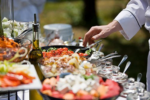 A caterer puts the finishing touches on the food at an outdoor wedding