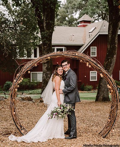 Young wedded couple pose by the vine arch at the Rough & Ready Vineyards. Photo by Mindful Media Photography 