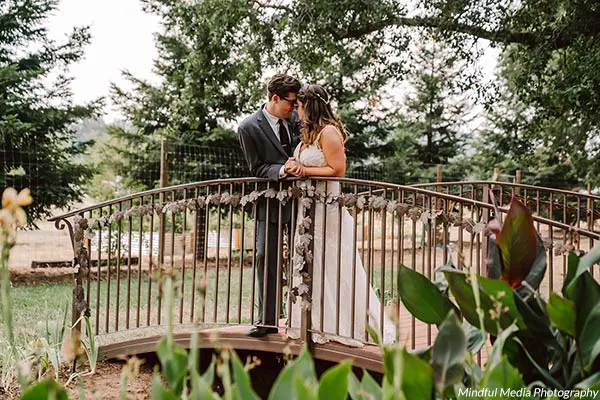 A bride and groom share a tender moment together on a bridge