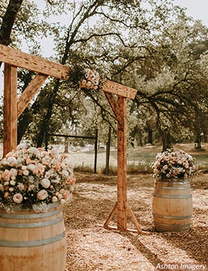 Roses in a springtime palette decorate an archway and wine barrels. Photo by Ashton Imagery