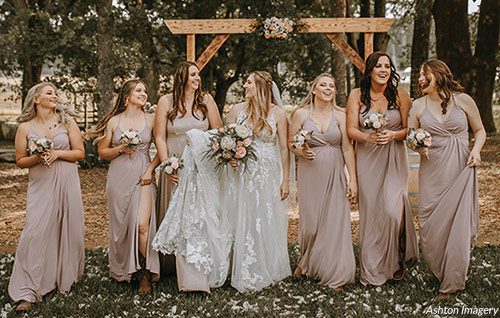 A bride walks with her bridesmaids who are wearing blush pink for her spring wedding. Photo by Ashton Imagery