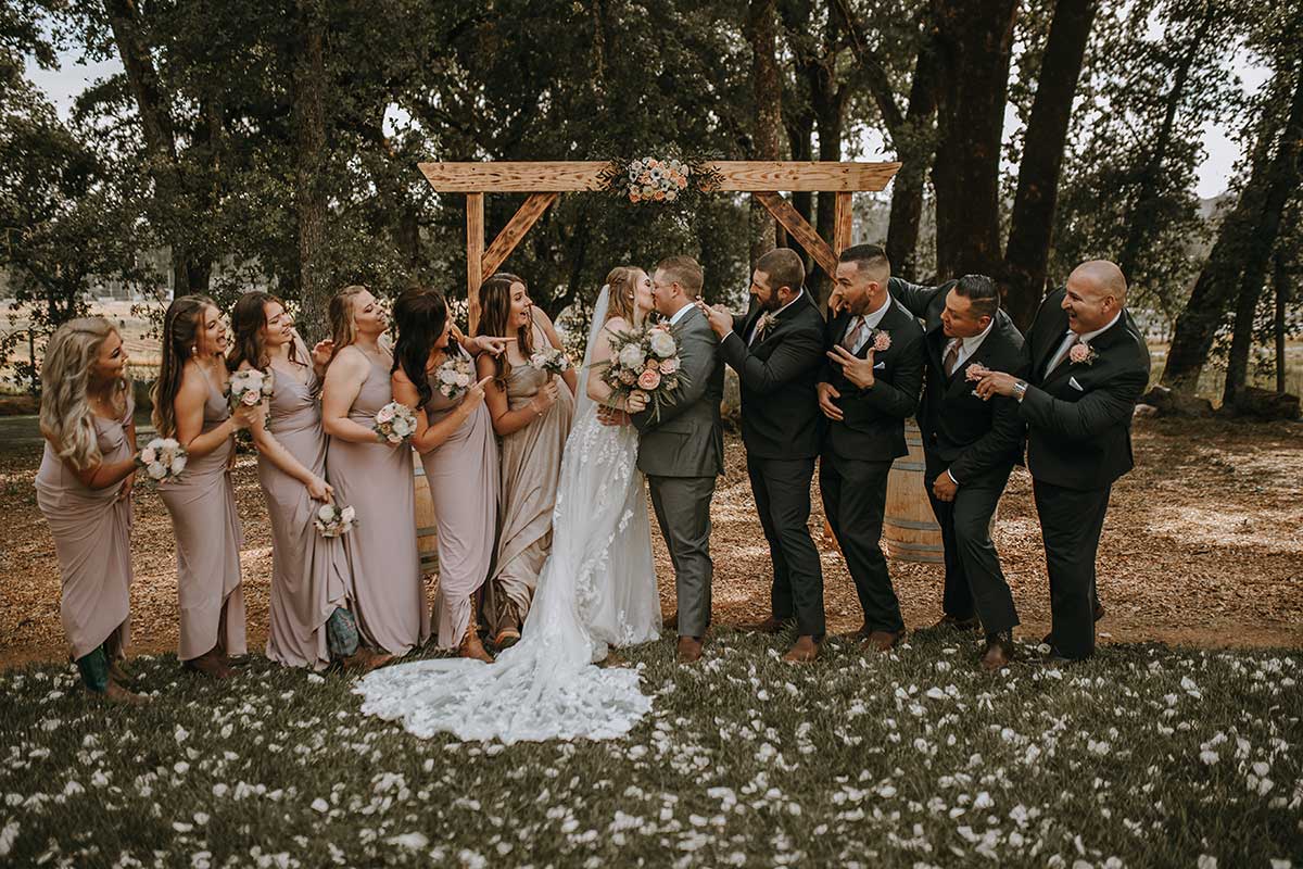 Bride and Groom kissing near wedding party