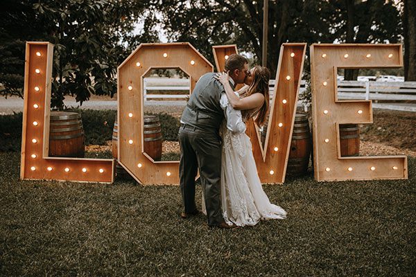 rentals, couple share a kiss in front of Love sign