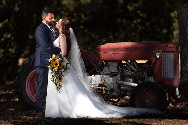 Bride and Groom Embracing navy blue sunflowers antique tractor in background