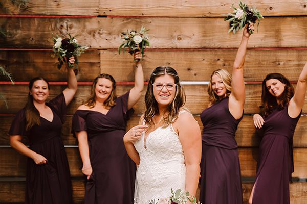 Bride and bridesmaids by wooden fence