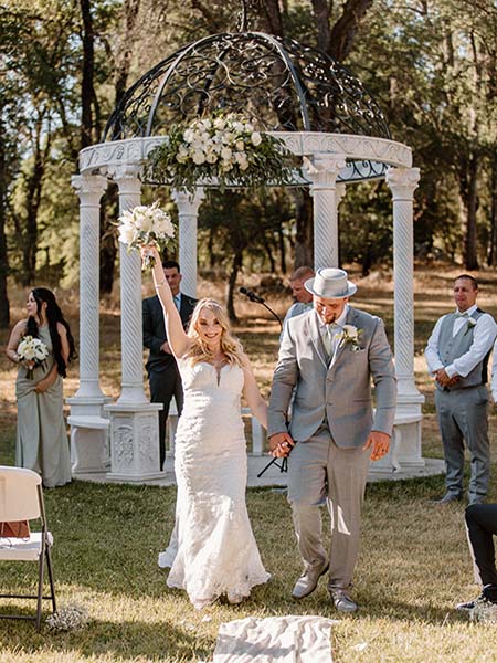 Bride holding up bouquet while leaving gazebo