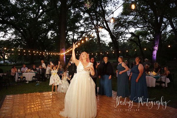Bride tossing bridesmaids bouquet. Photo by Darling Photography