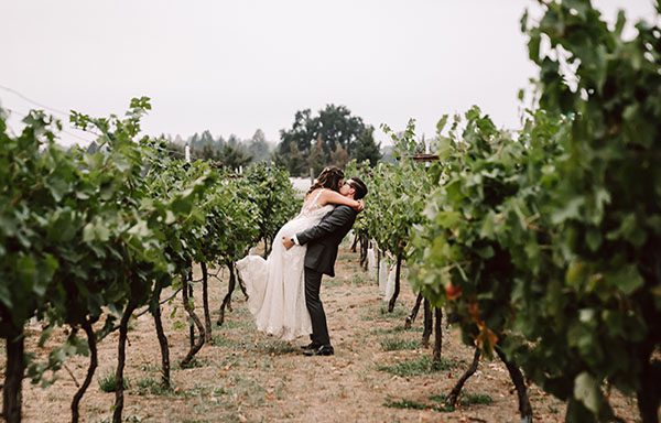 Groom holding up bride in vineyard