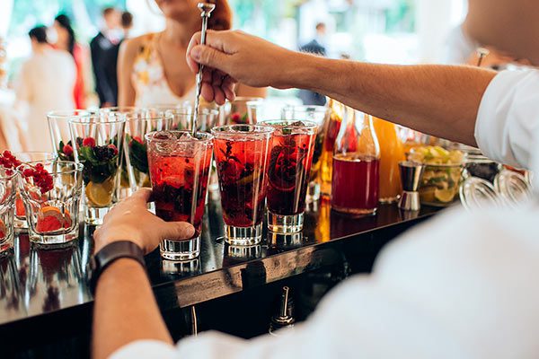 Bartending vendor hand-making cocktails at an outdoor wedding
