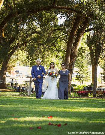 A bride is escorted down the aisle by her father and mother. Photo by Camden Ashley Photography