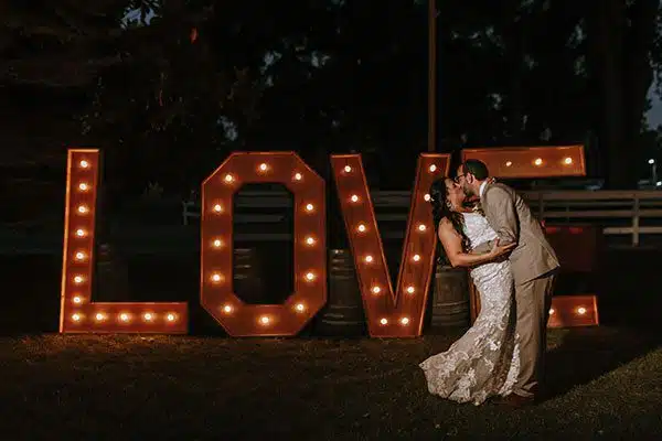 bride and groom kissing near the LOVE sign