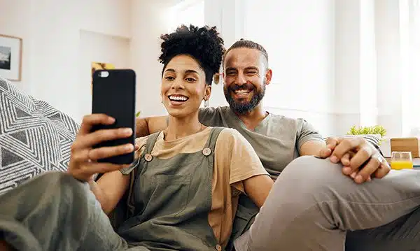 wedding-planning-apps Bi-racial couple visit a few wedding planning apps together on their sofa