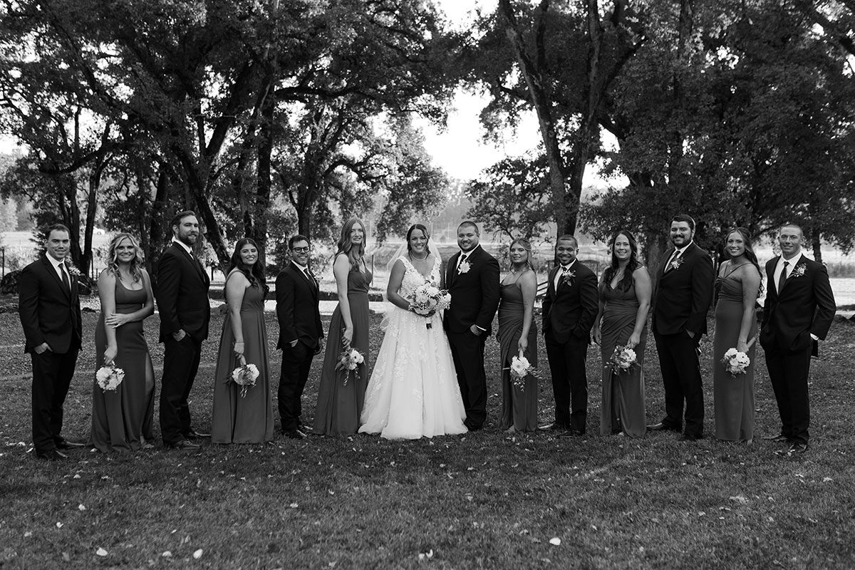 Winona and Tanner pose with their wedding party in black and white photo