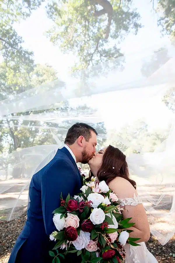 Brandon and Brooke, the groom and bride, kiss under her veil