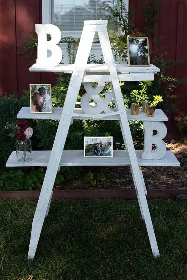 Painted ladder displaying photos of the couple and wedding decor. 