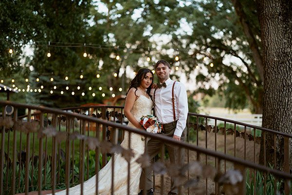 Smiling young bride and groom stand on a footbridge. Photo by Heidi Peinthor Photography 