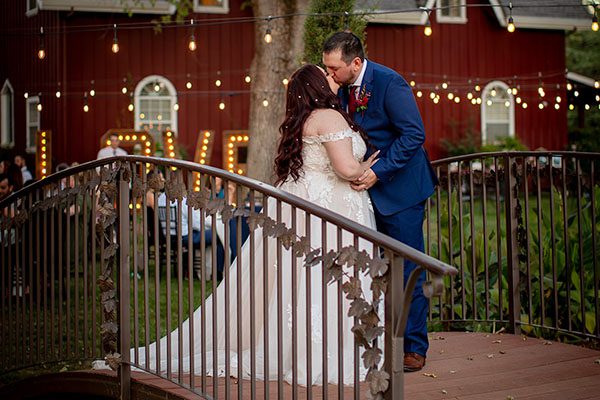 A bride and groom kiss at the footbridge at dusk. Photo by A Moment of Joy Photography