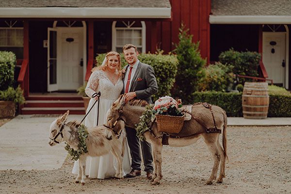 Bride and groom pose in front of the guesthouse with two donkeys. Photo by Dream Capture Studios