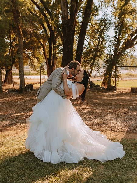 Groom dips his bride while kissing under the oaks. Photo by Ashton Imagery