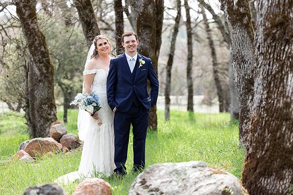 Bride and groom posing under oak trees. Photo by Andrew and Melanie Photography