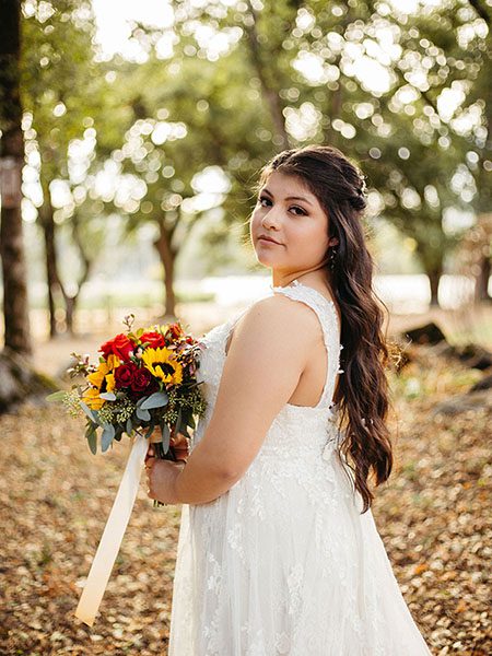 Bride looking over her shoulder, surrounded by oak trees. Photo by Bryan Gallagher Photography
