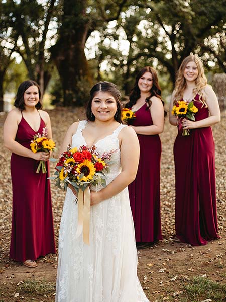 Smiling bride and three of her bridesmaids standing under heritage oaks. Photo by Bryan Gallagher Photography
