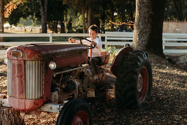 Boy playing on vintage tractor. Photo by Rebekah Townley Photography
