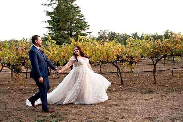 A bride and groom stroll leisurely through the Rough & Ready Vineyards. Photo by A Moment of Joy Photography