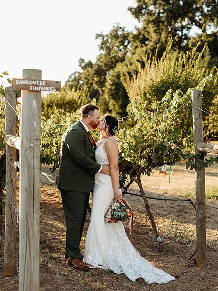 Groom kisses his bride at the Rough & Ready Vineyards. Photo by Rebekah Townley Photography