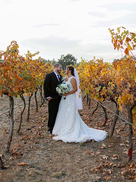 Groom and bride gaze at each other lovingly in the vineyards. Photo by Elizabeth Jane Photography