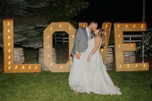 sign-dt Danielle and Timothy kiss by the marquee letters that spell LOVE