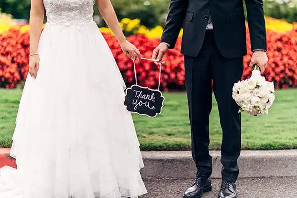 Cropped photo of married couple holding thank you sign
