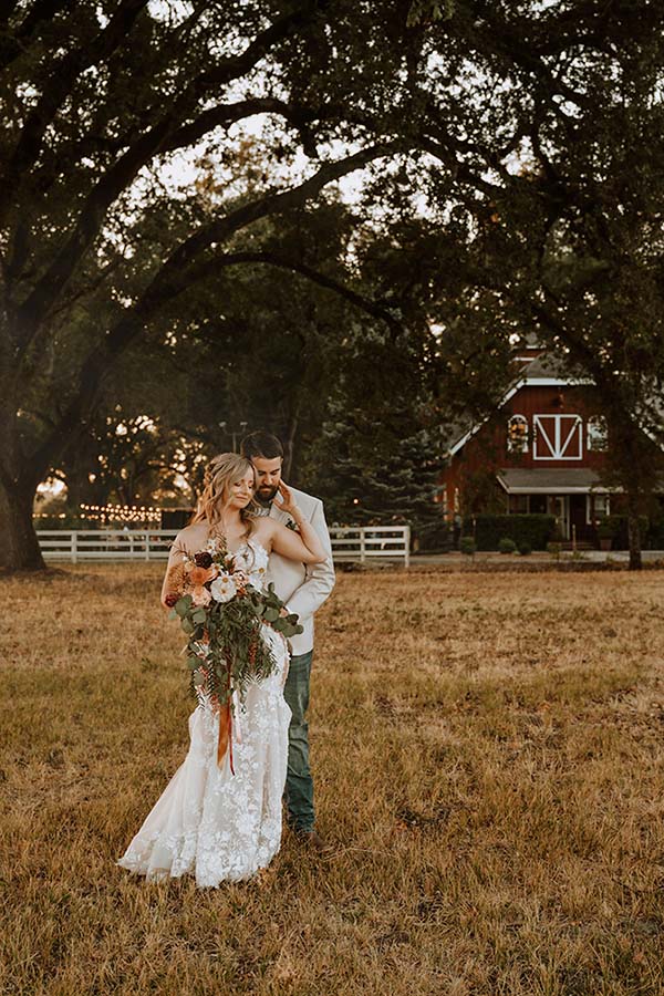 Maddy and Kasey embrace with the guesthouse in the background. Photo by Dream Capture Studios