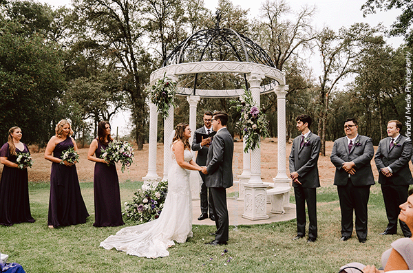 Happy couple holding hands by gazebo, inspired by Italian wedding venues. Photo by Mindful Media Photography