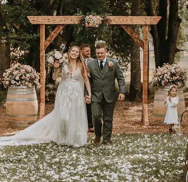 bride and groom in front of wedding arch