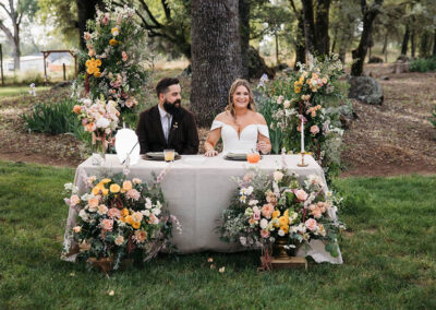 Bride and groom at their reception table with beautiful flowers in front