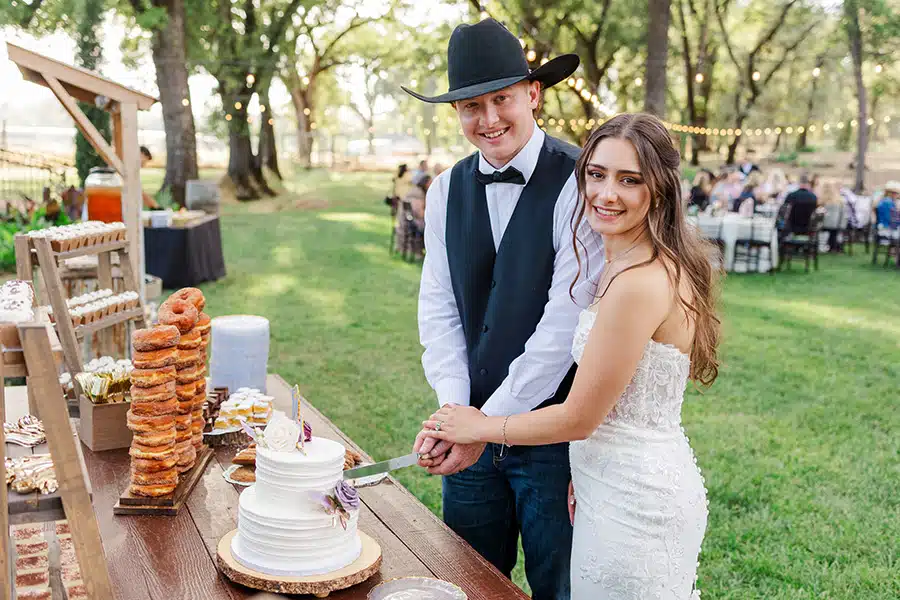 cake-kt Tuff and Kaylee pause for a photo while cutting into their wedding cake