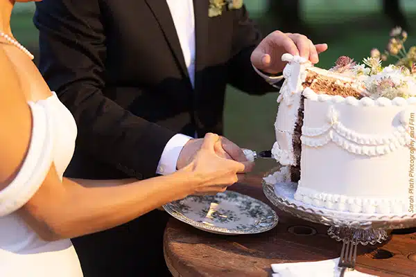 Close up shot of a newly-married couple cutting their wedding cake together. Photo by Sarah Plath Photography and Film