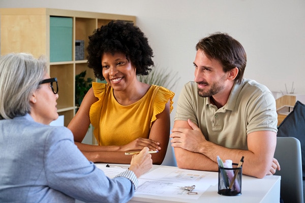 Young engaged couple meet with an insurance agent after learning what wedding insurance is